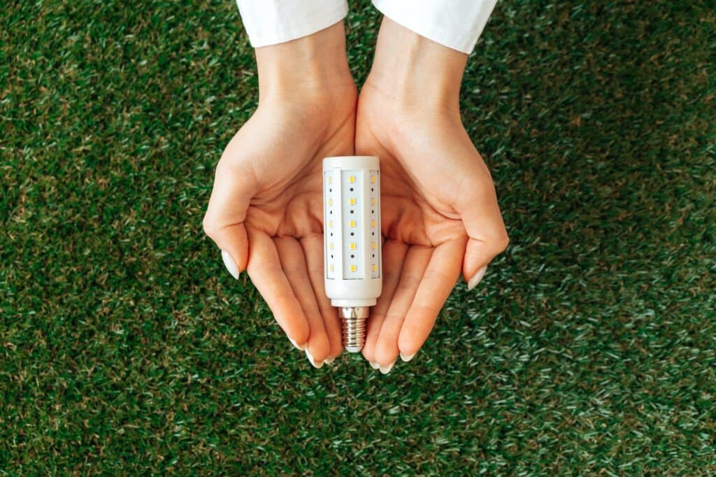 Woman holding lamp in hands above the grass